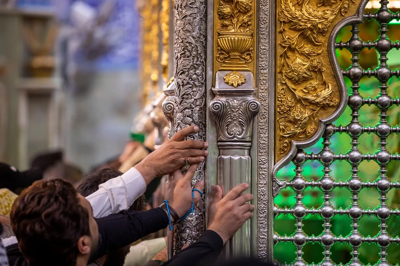 Worshippers' hands resting on the lattice of a shrine.